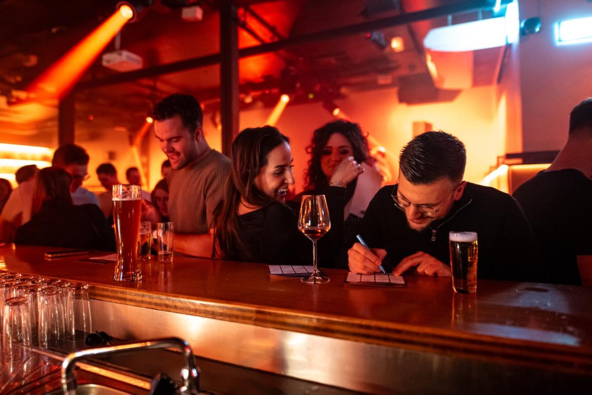 Freunde füllen ihre Bingokarte an der Theke einer Kneipe aus